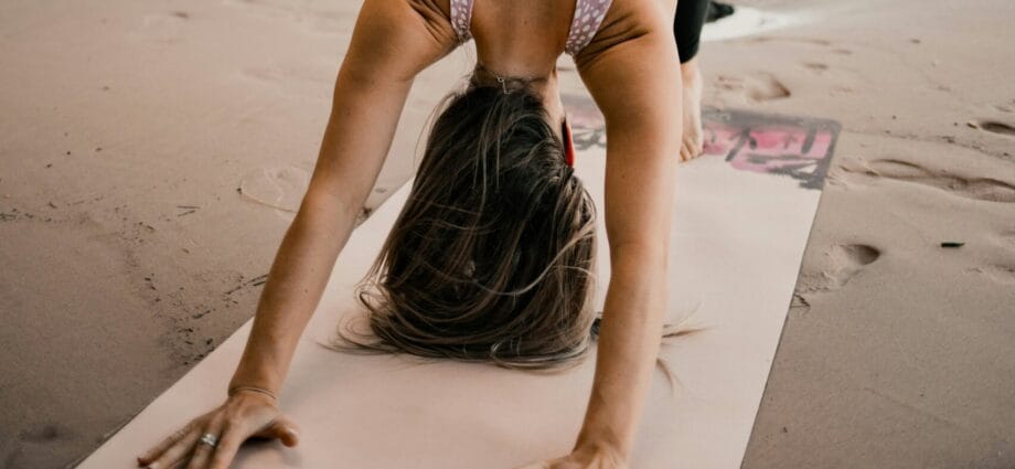 woman doing yoga on the sand under the tree